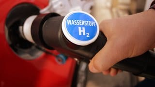 Ein Schild mit einem blauen Tankstellenzeichen, darunter die Worte Wasserstoff H2: Die einzige öffentliche Wasserstofftankstelle in RLP in Koblenz macht dicht. 