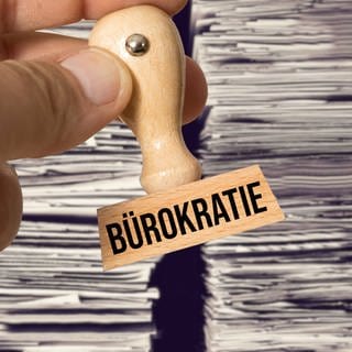 Bürokratie-Stempel vor Aktenhaufen