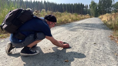 Wolfgang Burens macht zur Dokumentation ein Foto der Ödlandschrecke.