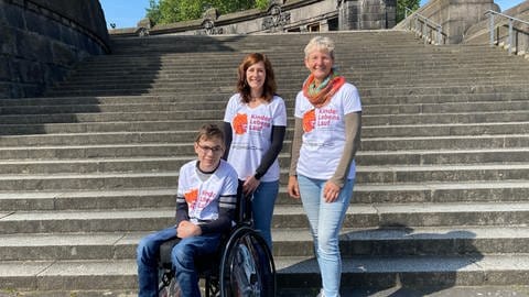 Ein Junge im Rollstuhl und zwei Frauen auf den Treppen am Deutschen Eck - Denkmal in Koblenz 
