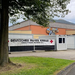 Ein Gebäude an einem Parkplatz mit Absperrband. Seit Ende März 2022 sind in der Turnhalle in Neuwied-Niederbieber Geflüchtete untergebracht.