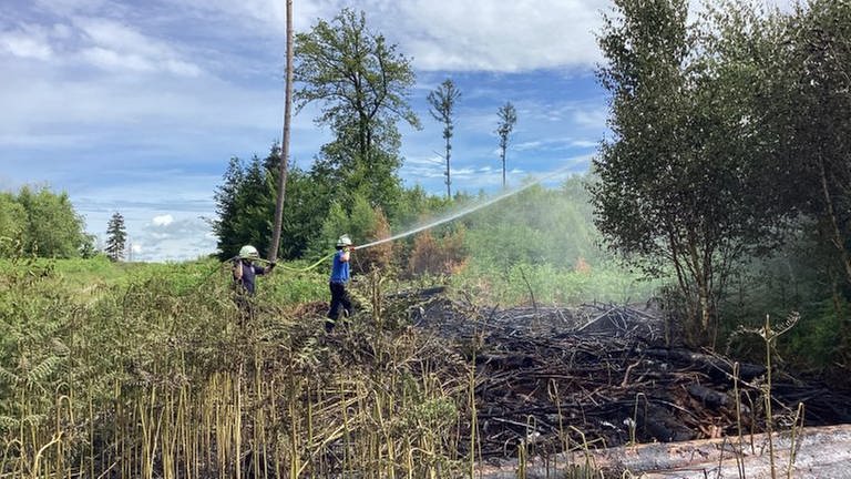 Zwei Feuerwehrmänner löschen einen Brand in einem Waldstück bei Ransbach-Baumbach