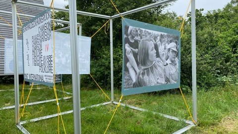 Ein Banner mit einem Foto hängt an einem Metallgestell. Mit einer Ausstellung will die Arbeitsgemeinschaft Burg Waldeck, die das Waldeck Open Air veranstaltet, die Geschichte des ersten Open-Air-Festivals Deutschlands zeigen.