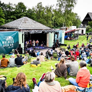 Menschen sitzen vor der Bühne beim Waldeck-Open-Air-Festival.