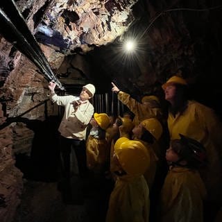 Ein Grubenführer führt eine Gruppe Kinder mit ihren Erzieherinnen durch die Grube Bindweide.