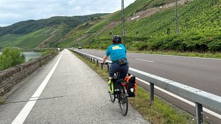 Eine Radfahrerin fährt am Rhein entlang Richtung Boppard