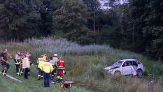 Einsatzkräfte an der Unfallstelle vor einem Autowrack: In Bayern ist auf dem Rückweg aus dem Urlaub eine Familie aus dem Kreis Mayen-Koblenz verunglückt. Es gab zwei Tote. 