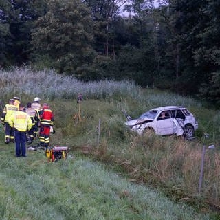 Einsatzkräfte an der Unfallstelle vor einem Autowrack: In Bayern ist auf dem Rückweg aus dem Urlaub eine Familie aus dem Kreis Mayen-Koblenz verunglückt. Es gab zwei Tote. 