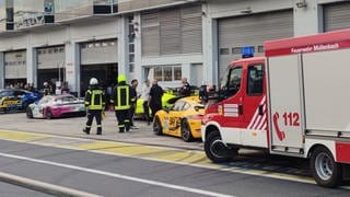 Feuerwehrleute laufen vor Box 27 in der Boxengasse des Nürburgrings. Bei der Explosion einer Druckluftflasche hinter der Box im Bereich des Fahrerlagers wurden etliche Menschen verletzt. 