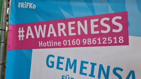 Ein großes Banner mit der Aufschrift "'AWARENESS" und einer Telefonnummer: Bei Rhein in Flammen 2024 gibt es erstmals ein Awareness-Team. Es kümmert sich um Menschen, die sich bedroht oder belästigt fühlen oder auch sonst Hilfe brauchen oder sich unwohl fühlen. 