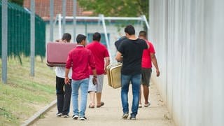 Junge Männer mit Koffern vor einer Aufnahmeeinrichtung für Asylsuchende in Rheinland-Pfalz