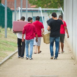 Junge Männer mit Koffern vor einer Aufnahmeeinrichtung für Asylsuchende in Rheinland-Pfalz