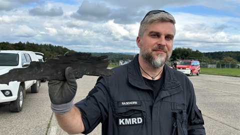 Sven Rasehorn vom Kampfmittelräumdienst hält einen Teil der Bombe in der Hand, die in Koblenz kontrolliert gesprengt wurde