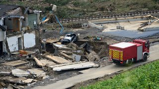 Feuerwehrauto vor zerstörtem Haus 