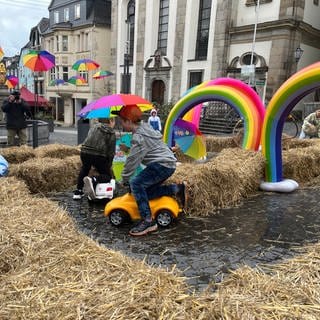 Kinder auf einem Bobbycar fahren durch einen Parcous aus Strohballen