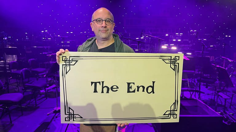 Der Intendant des Theaters Koblenz, Markus Dietze, hält ein Schild mit der Aufschrift "The End" in der Hand. 