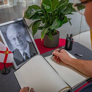 Ein Bild des Koblenzer Ex-Oberbuergermeisters Eberhard Schulte-Wissermann (SPD) steht vor einem Kondolenzbuch: Das liegt in der Stadtbibliothek im Forum Confluentes in Koblenz aus, damit sich Bürgerinnen und Bürger eintragen können.