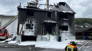 Von dem ausgebrannten Haus in Daaden ist nur eine Ruine übrig, umgeben von weißem Löschschaum. Bei dem Feuer ist ein Mensch ums Leben gekommen. 