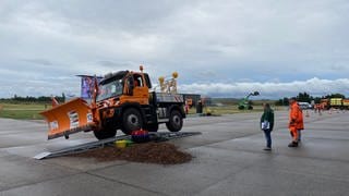 Ein Schneepflug fährt bei der EM im Schneepflugfahren auf dem Flughafen in Mendig etwas schief über eine Rampe über einem kleinen Erdhügel. 