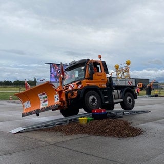 Ein Schneepflug fährt bei der EM im Schneepflugfahren auf dem Flughafen in Mendig etwas schief über eine Rampe über einem kleinen Erdhügel. 