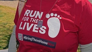 Demo-Teilnehmerin mit rotem T-Shirt und Aufschrift "Run for Their Lives"