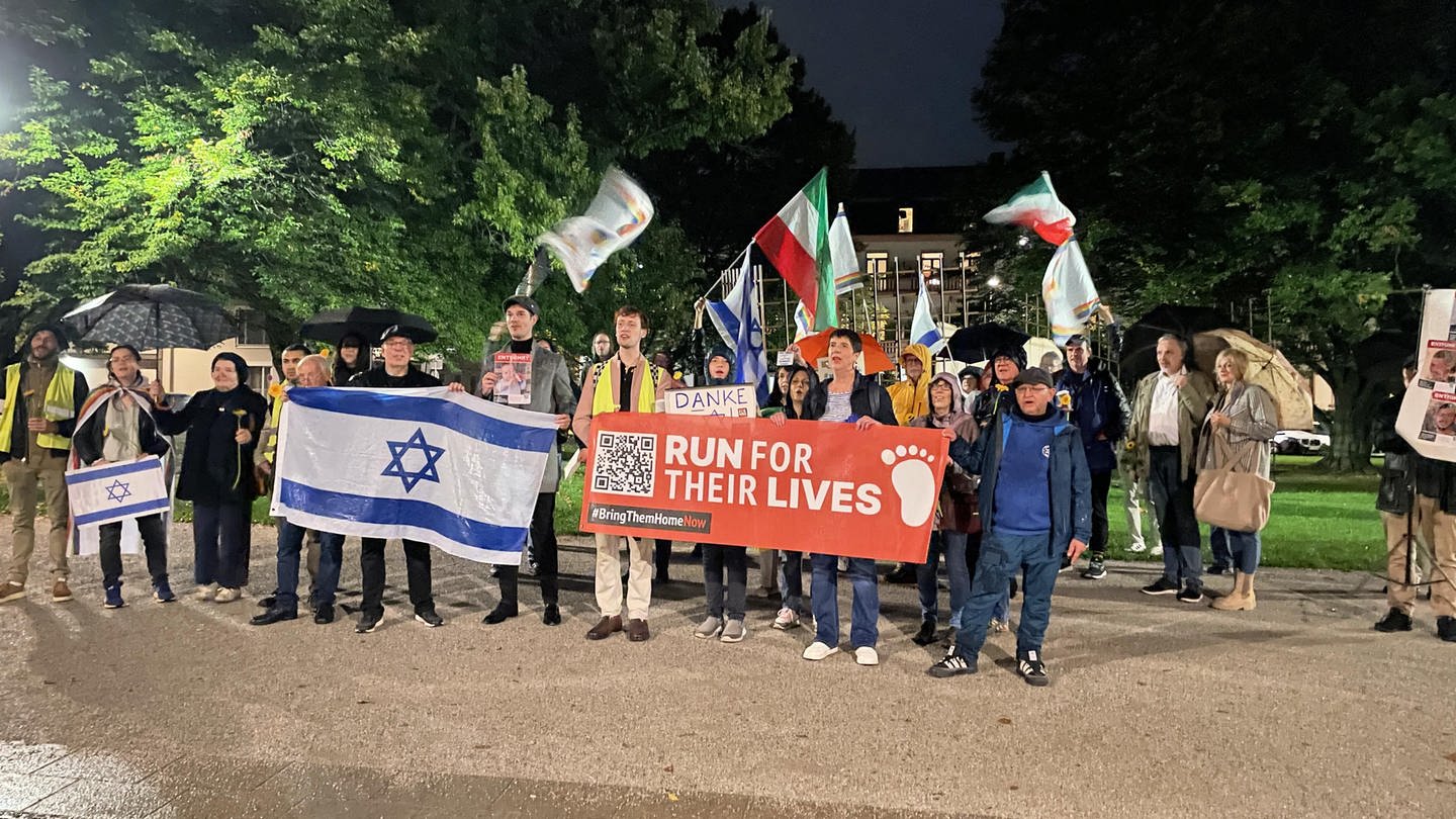 Etwa 50 Menschen stehen mit Transparenten und Israel-Fahnen vor dem Mahnmal für die Opfer des Nationalsozialismus in Koblenz.