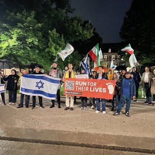 Etwa 50 Menschen stehen mit Transparenten und Israel-Fahnen vor dem Mahnmal für die Opfer des Nationalsozialismus in Koblenz.