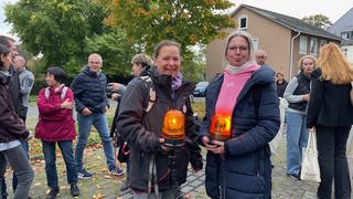 Mehrere Teilnehmer stehen bei einer Mahnwache mit Leuchtsignalen vor dem Kreistag in Altenkirchen