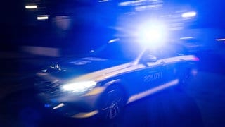 Ein Polizeifahrzeug fährt mit Blaulicht an einem Gebäude vorbei.