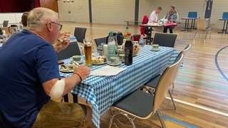 Ein Mann isst nach der Blutspende Weißwurst in Kobern-Gondorf.