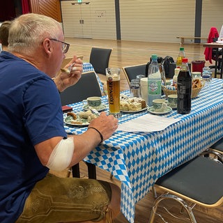 Ein Mann isst nach der Blutspende Weißwurst in Kobern-Gondorf.