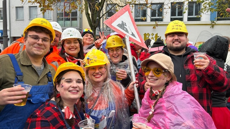 Eine Gruppe von jungen Menschen ist als Bauarbeiter verkleidet und feiert den Karnevalauftakt 202425 in Koblenz. 