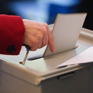 Eine Frau wirft einen Wahlzettel in die Urne zur Bundestagswahl.