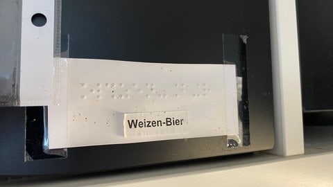 Ein Aufkleber in Blindenschrift an einem Küchenschrank in einer Café-Küche 