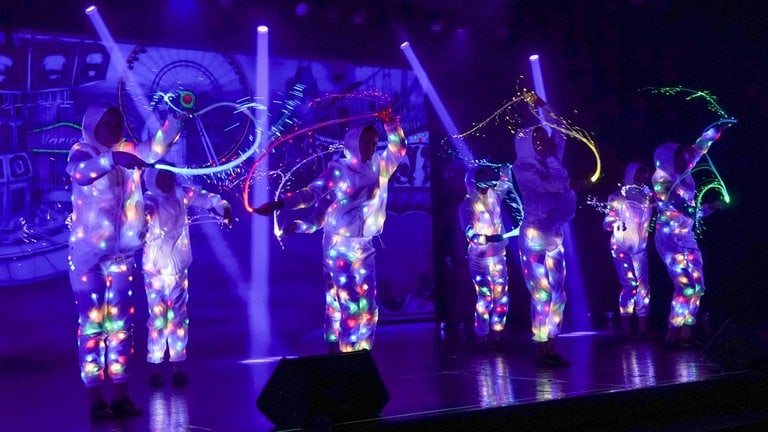 Tänzer der Musical-AG der Integrierten Gesamtschule in Plaidt schwenken bunte Lichter in einer dunklen Bühne