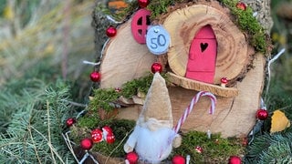 Ein mit roten Kugeln dekoriertes Wichtelhaus mit einem Wichtel steht am Wichtelweg in Kottenheim. Das ist ein schönes Ausflugsziel im Advent und an Weihnachten 2024. 