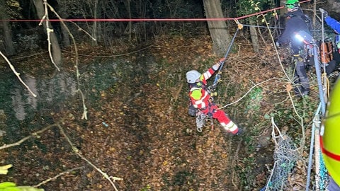 Ein Höhenretter seilt sich in den tiefen Schacht ab, in dem die Jugendlichen verunglückt sind.