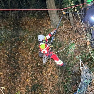 Ein Höhenretter seilt sich in den tiefen Schacht ab, in dem die Jugendlichen verunglückt sind.