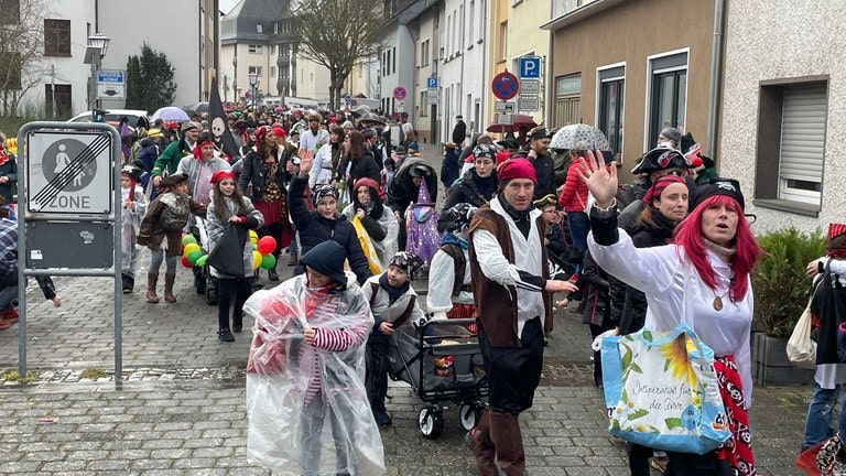 Eine Gruppe als Piraten verkleideter Kinder und Eltern winkt beim Kinderkarnevalsumzug in Mayen