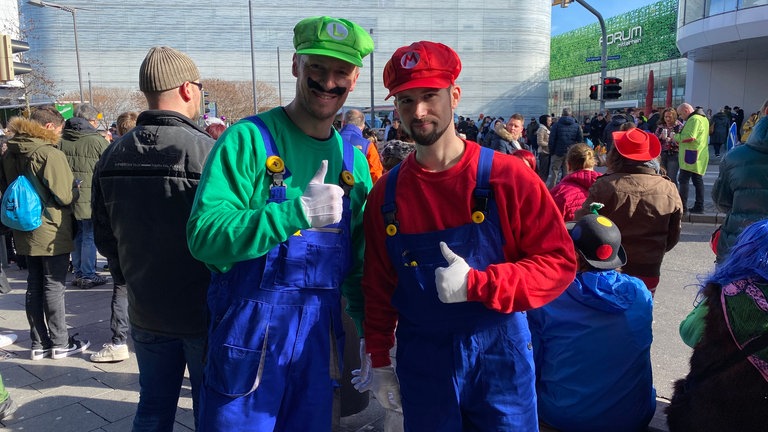 Diese beiden Zuschauer beim Rosenmontagszug 2023 in Koblenz in ihren "Mario Kart"-Kostümen erinnern an die ersten Videospiele. 