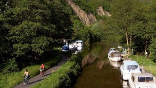 Radfahrer fahren auf dem Lahnradweg entlang der Lahn. Der Radweg ist jetzt auch durchgehend befahrbar.