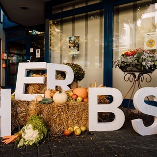 Kürbise mit großen Buchstaben davor, auf denen "Herbst" steht.