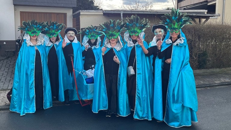 Rosenmontag 2024 in Urmitz am Rhein: Damen mit blauen Masken und blauen Umhängen