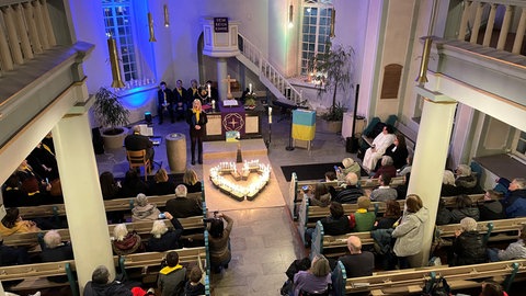 Die etwa 200 Besucher haben in der Kirche Kerzen in Form eines Herzens aufgestellt.