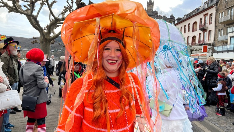 Gut beschirmt mit einem orangenen Regenschirm - eine Frau beim Rosenmontagsumzug in Cochem.