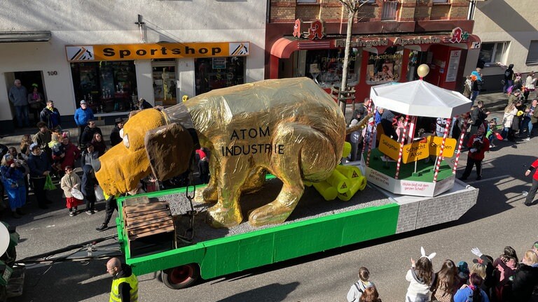 Ein Hund scheißt Atomfässer aus - das zeigt ein Motivwagen beim Rosenmontagszug 2023 in Koblenz