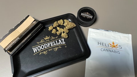 Cannabisblüten, ein sogenannter Grinder zum zerkleinern der Blüten und sogenannte Papers, um einen Joint zu drehen.