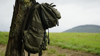 Ein Wanderrucksack hängt an einem Baum am Wanderweg "Zauberwald" bei Helferskirchen im Westerwald. 