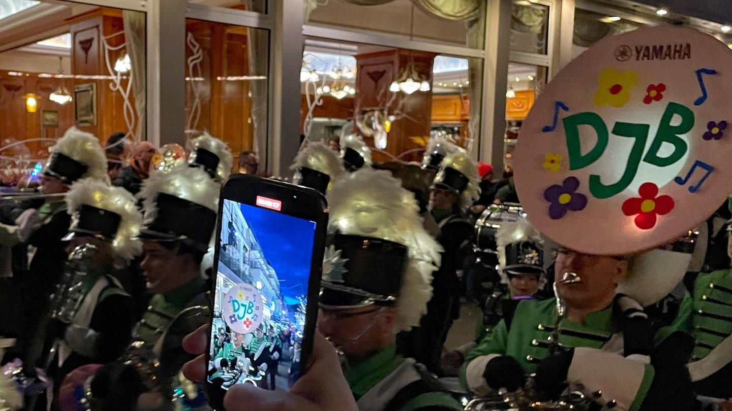 Eine Hand hält ein Handy und macht ein Foto von einer Musikkapelle beim Abendumzug in Boppard 2024