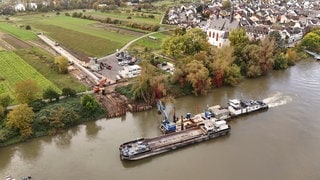 Luftbild: Am Ufer der Rheininsel Niederwerth liegt die Röhre bereit, um verlegt zu werden, zwei Arbeitsschiffe liegen im Rhein, um die Arbeiten zu unterstützen.